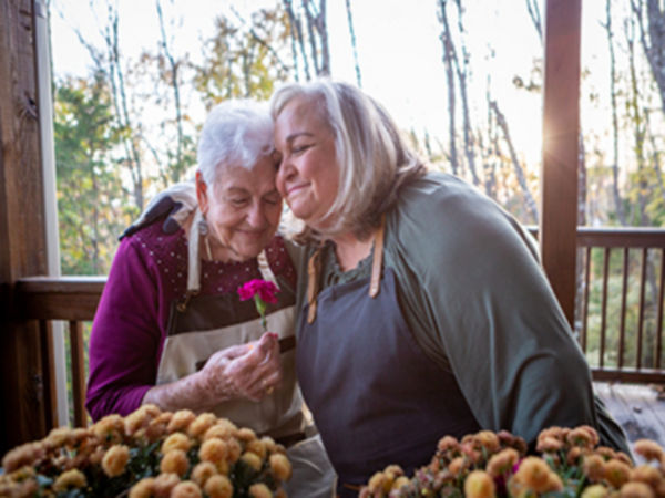 two women hugging and holding a flower