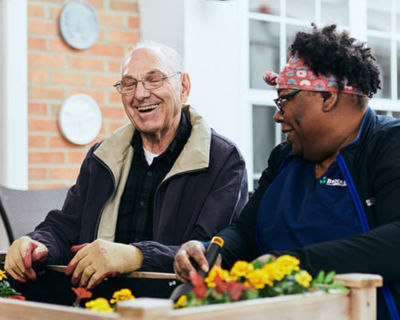 Man gardening with associate and laughing