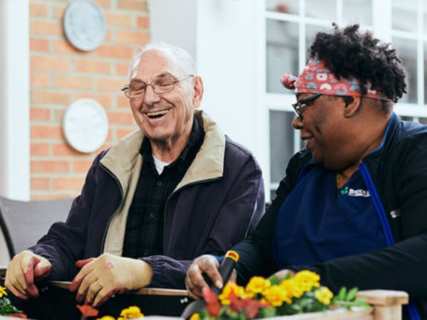 Man gardening with associate and laughing